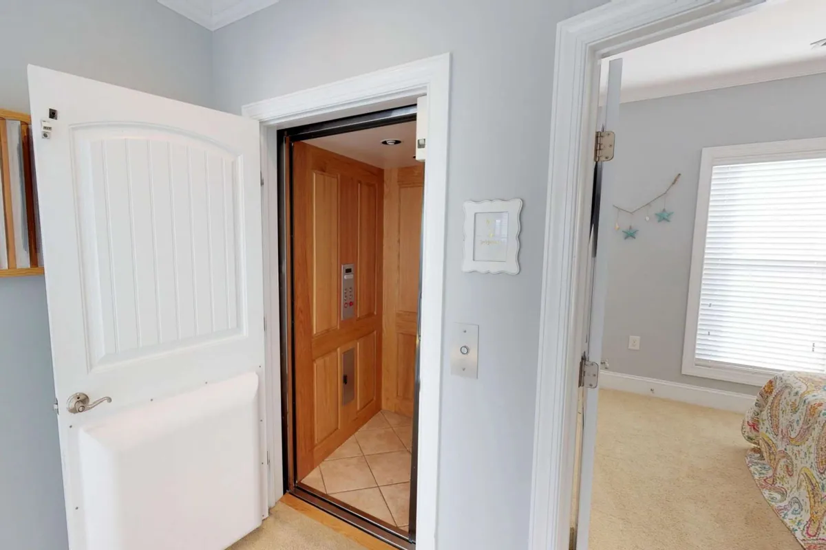 This image depicts the in-home elevator with its doors open, situated near doorways leading to a bedroom. The clean lines and accessible entryways emphasize ease of movement throughout the multi-level home.