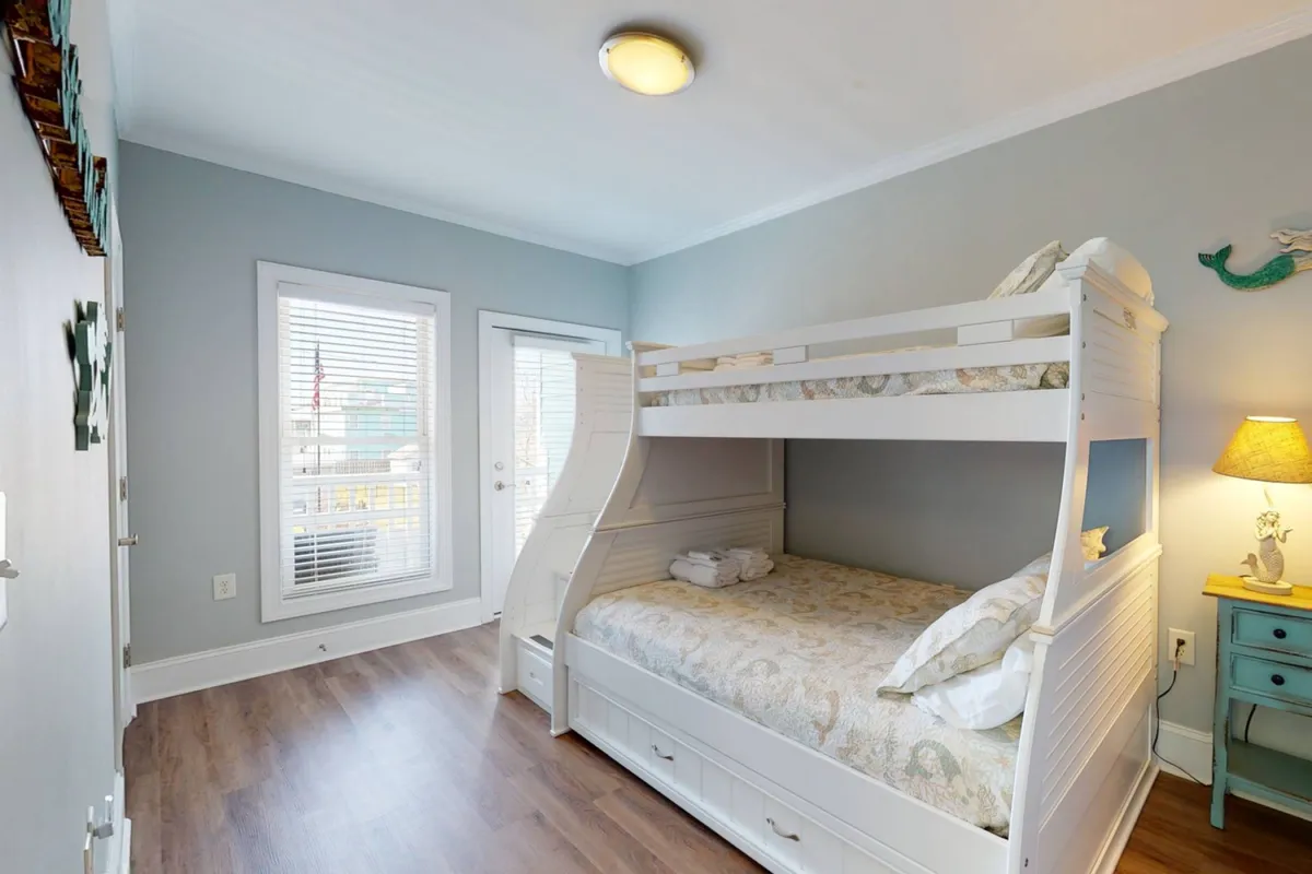 A dedicated bunk room with a sturdy bunk bed, soft lamp lighting, and a window that brings in gentle daylight. The space is designed to be both fun and inviting, perfect for children or groups sharing the room.
