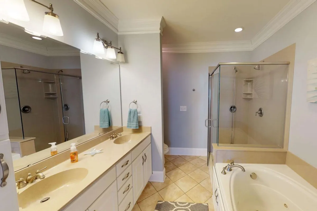 A luxurious bathroom with a double sink vanity, glass shower enclosure, and a freestanding bathtub. Mirrored cabinets and elegant lighting create a spa-like environment, ideal for unwinding after a day of adventure.